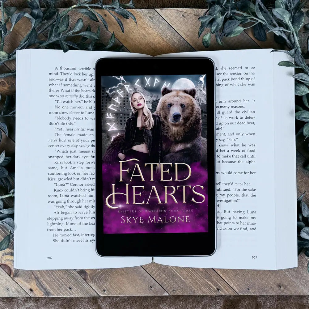 The shifter paranormal romance novel Fated Hearts by Skye Malone on an ereader lying on the paperback edition of the same novel, which is all on a wooden table surrounded by green leafy plants.