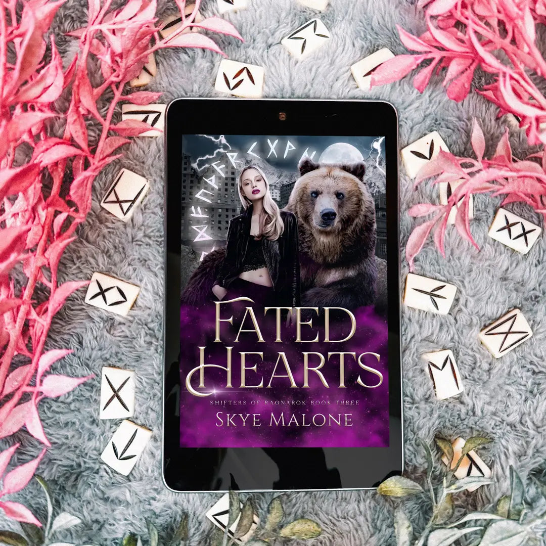 The post-apocalyptic paranormal romance novel Fated Hearts by Skye Malone on an ereader tablet lying on a gray blanket surrounded by white-bone runes and pink flowers.